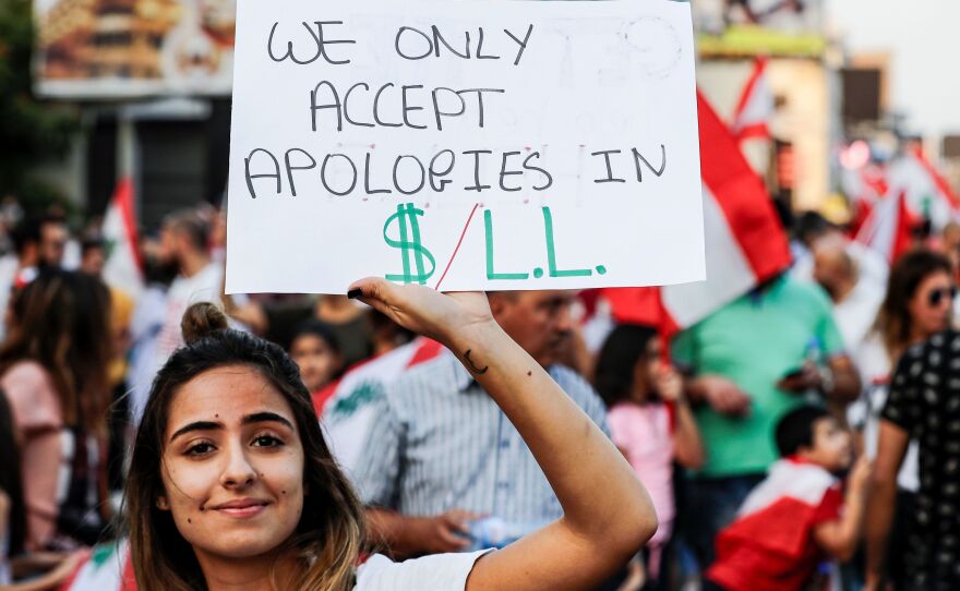 A Lebanese woman holds up a sign demanding that the country's ruling elites pay up on the sixth day of protests